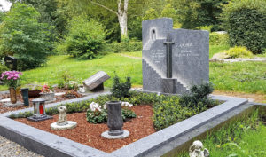 Doppelgrabstein mit Kreuz und pflegeleichter Grabgestaltung mit Rindenmulch.