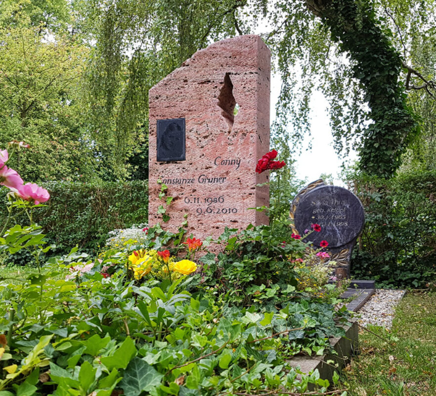Naturbelassener Grabstein Einzelgrab mit Rosen und Efeu / Grabstein mit Öffnung roter Travertin