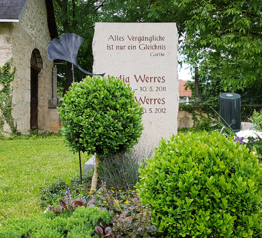 Gestaltung eines Urnengrabes - rustikaler Grabstein aus Kalkstein mit Ginkoblatt aus Bronze