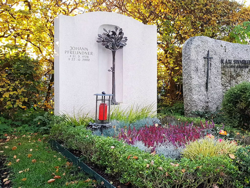 modernes Doppelgrabmal aus hellem Kalkstein mit großer Bronzeplastik - Herbstbepflanzung mit Stauden und Gräsern - Friedhof Vaterstetten/ München