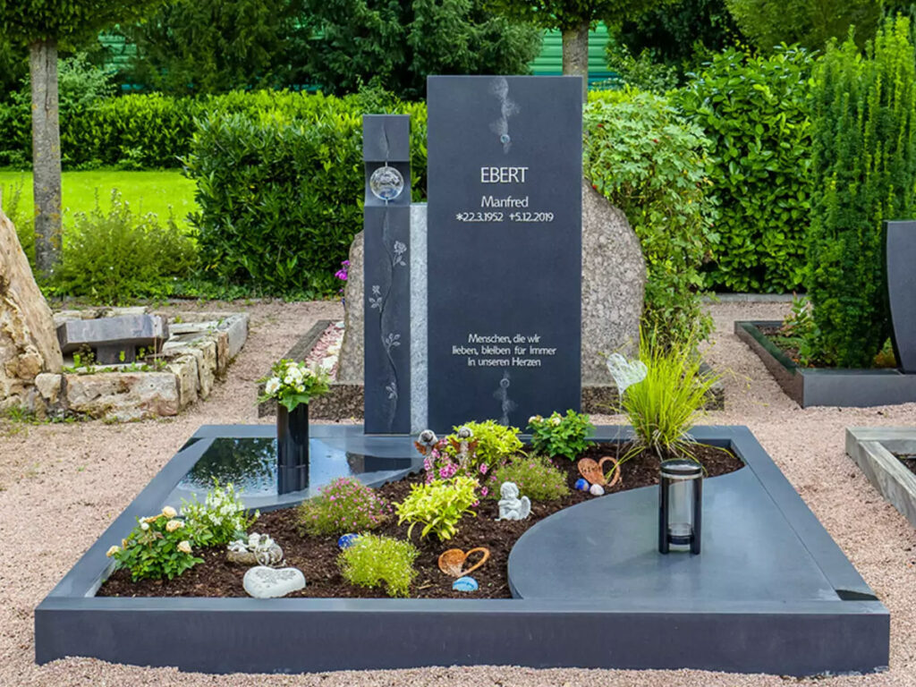 Ein Doppelgrabstein aus schwarzem Granit mit einer Glaskugel und Edelstahl-Einfassung sowie Abdeckplatte.