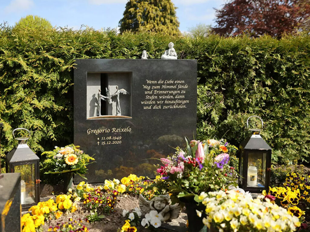 Polierter Doppelgrabstein, modernes Design, aus schwarzem Granit mit Öffnung und Engelfiguren aus Bronze - Grabgestaltung mit Frühlingsblühern und Grabdekoration