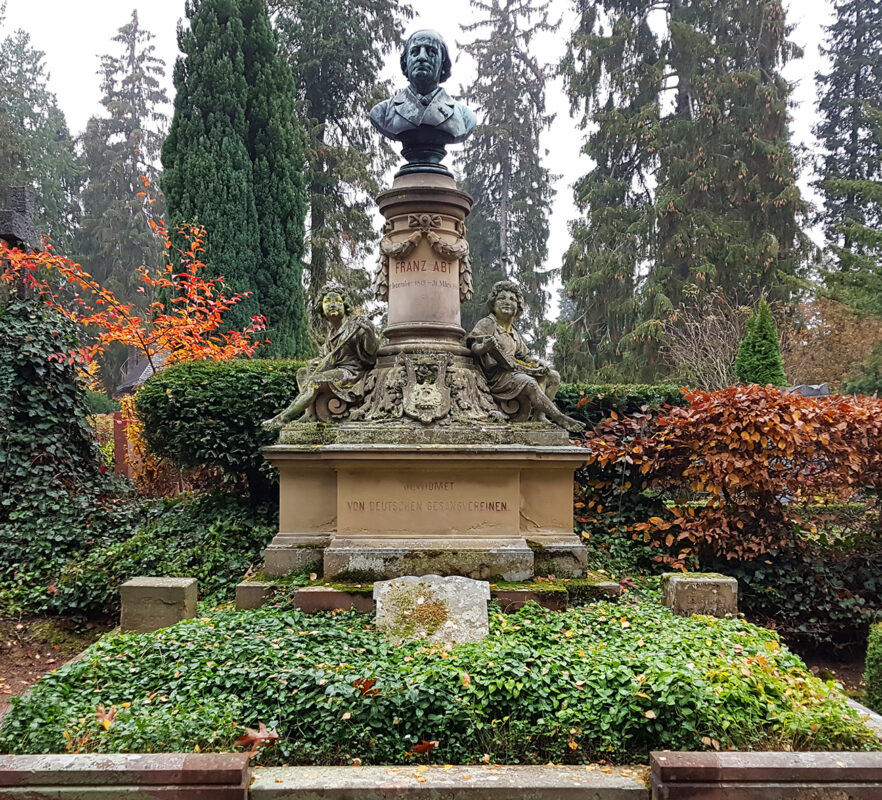 Säule mit Bronzebüste und musizierenden Engeln aus Sandstein