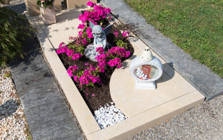 Impressionen vom Friedhof: geteiltes Grabmal mit berührenden Händen aus beigem Marmor
