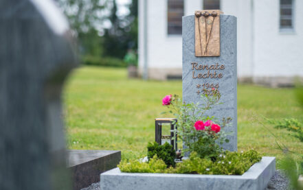 Impressionen vom Friedhof: Grabstein mit Bronzelement für ein Urnengrab aus Granit mit Einfassung