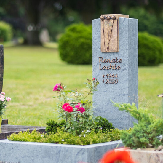 Modernes Urnengrab mit Einfassung und floralem Element aus Bronze