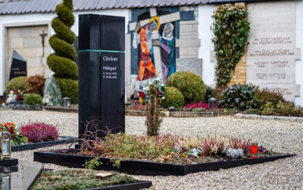 Impressionen vom Friedhof: Modernes Einzelgrab mit schwarzem Granitgrabstein und christlichem Kreuz-Symbol