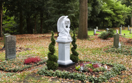 Impressionen vom Friedhof: Urnengrab mit einem weißen Grabengel aus Marmor auf einem Sockel