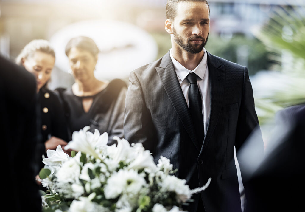 Trauerfeier am Grab mit Blumenschmuck