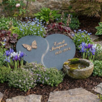 Dieses Bild zeigt eine außergewöhnlich naturnah gestaltete Grabstätte  die durch ihre herzförmige Symbolik und harmonische Einbettung besticht.