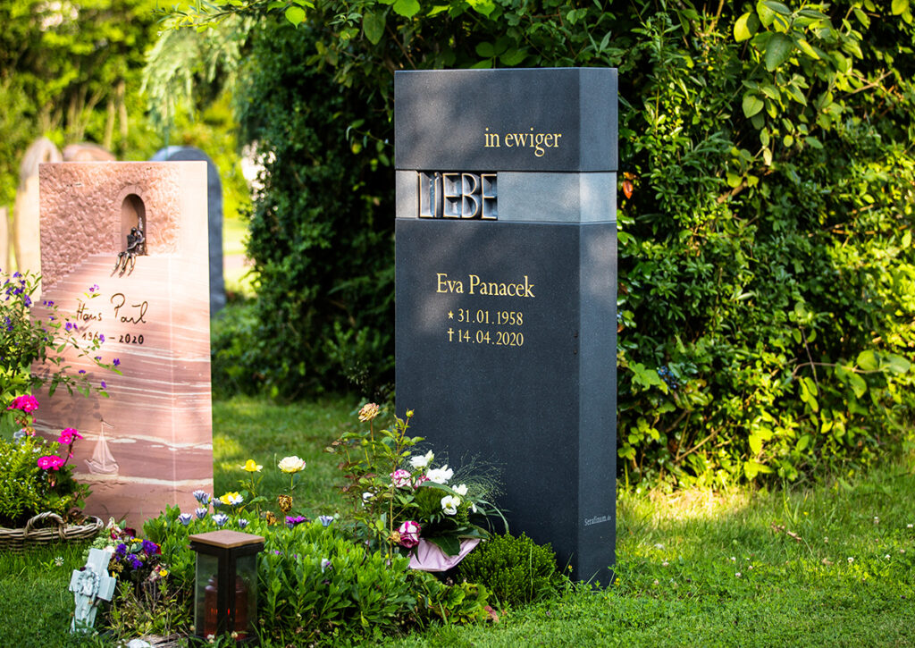 Stehender Urnengrabstein in modernem Design mit der Inschrift "Liebe" als Bronzeornament.