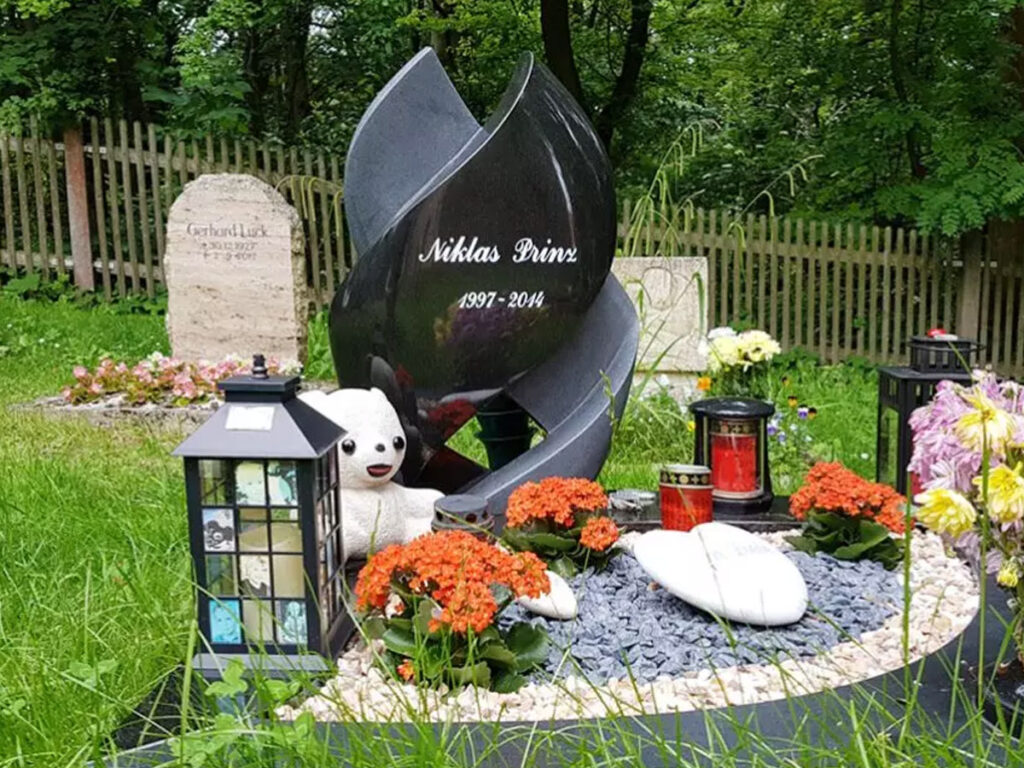 Moderner Grabstein für ein Kindergrab aus schwarzem Granit als Spirale gedreht mit Einfassung.