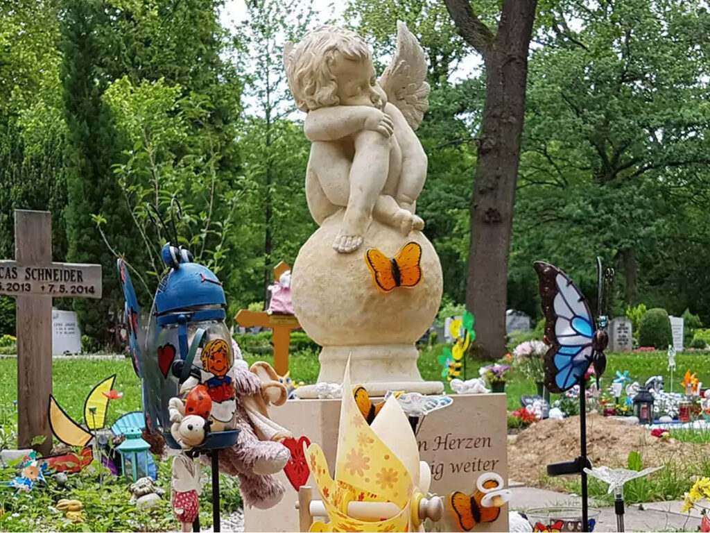 Kindergrab mit einer Engelfigur und Grabschmuck