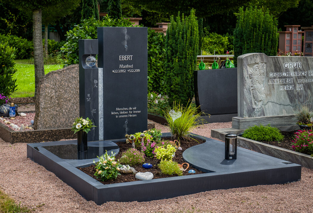 Bei einem Doppelgrabstein aus Naturstein bewegen sich die Anschaffungskosten meist zwischen 6.000 und 15.000 Euro. Die individuelle Beschriftung – ob als vertiefte Gravur oder mit Bronzebuchstaben – schlägt mit etwa 18 bis 30 Euro pro Zeichen zu Buche. Der fachmännische Aufbau inklusive Fundament durch einen Steinmetz variiert regional  liegt jedoch oft bei 800 bis 1.200 Euro. Eine optionale Natursteinumrandung mit Sockel ist inklusive Montage für etwa 2.800 bis 5.000 Euro erhältlich.