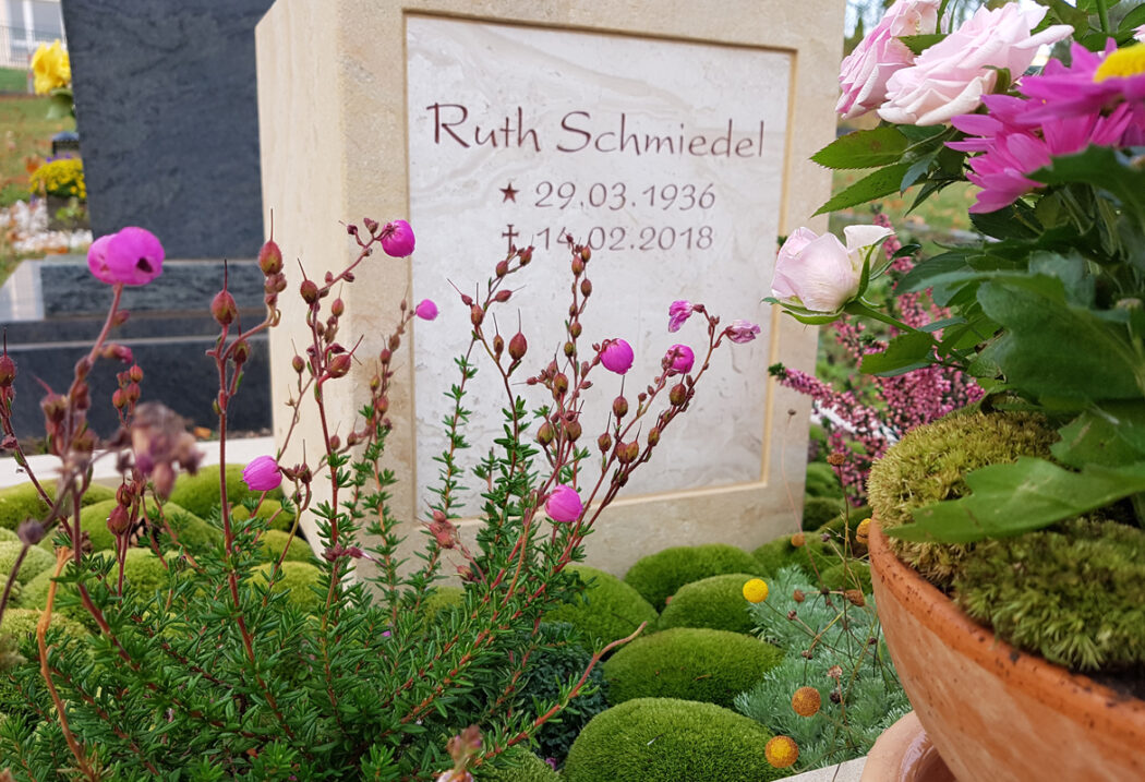 Die Inschrift „Ruth Schmiedel“  ergänzt durch Geburts- und Sterbedaten  ist dezent in den Stein eingearbeitet  was den Fokus auf die harmonische Gesamterscheinung lenkt.