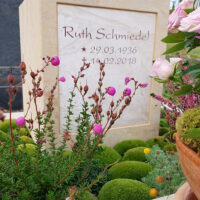 Die Inschrift „Ruth Schmiedel“  ergänzt durch Geburts- und Sterbedaten  ist dezent in den Stein eingearbeitet  was den Fokus auf die harmonische Gesamterscheinung lenkt.