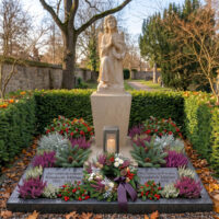 Allerheiligen Engel KI Großes Familiengrab mit einem betenden Grabengel aus hellem Sandstein mit Einfassung in dunklem poliertem Granit sowie zwei Gedenktafeln ebenfalls aus Granit. Geschmückt mit einem Kranz aus Herbstblumen und einer passenden EInpflanzung zu Allerheiligen.
