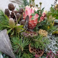 Allerheiligen Grabgesteck rosa Grabgesteck für Allerheiligen mit Zapfen Trockenblumen und rosa gefärbter Distel im Mittelpunkt